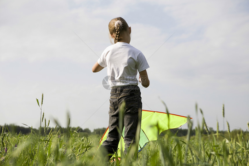 年轻女孩在野外飞行风筝一个女孩头发长度孩子们金发女孩们绿色孩子马尾辫田园图片