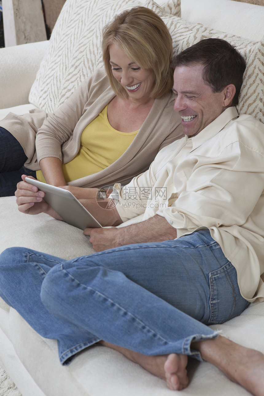 情侣坐着看数字书生活服装女士夫妻电子两个人媒体男人阅读牛仔裤图片