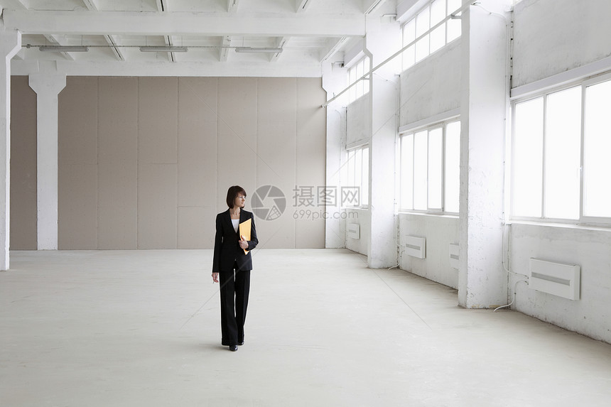 女商务人士在空仓库里站着夹克文件夹商务裤装短发经营窗户个体成人自雇图片