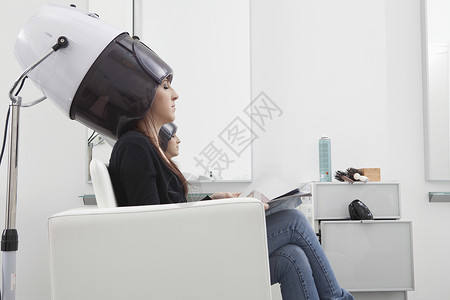 女客户在理发厅坐在干衣帽下高清图片