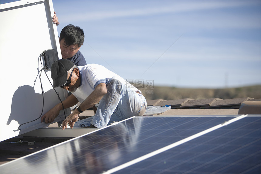 两个人在屋顶上做太阳能电池板面板工作团队工人环境光伏能源环境问题男士起重团体合作图片