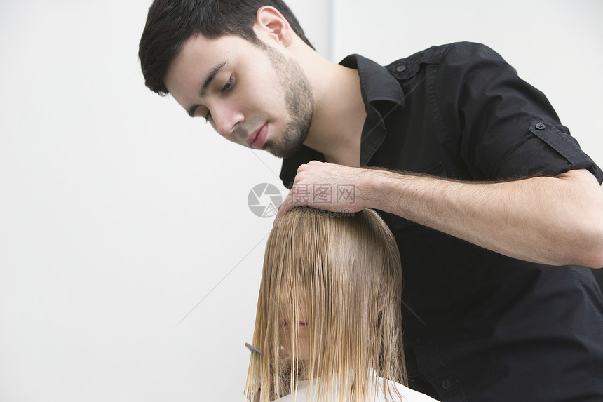 男人在理发师身上剪年轻女人的头发金发女郎成年顾客美发师女士女性成人美发两个人专注图片