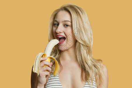 一个黄色香蕉一个美丽的金发美女的肖像 以彩色背景吃香蕉背景