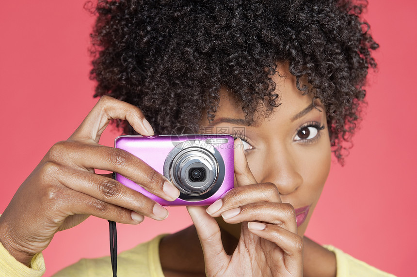 一名非裔美国女性在彩色背景上拍摄相机照片的肖像图片