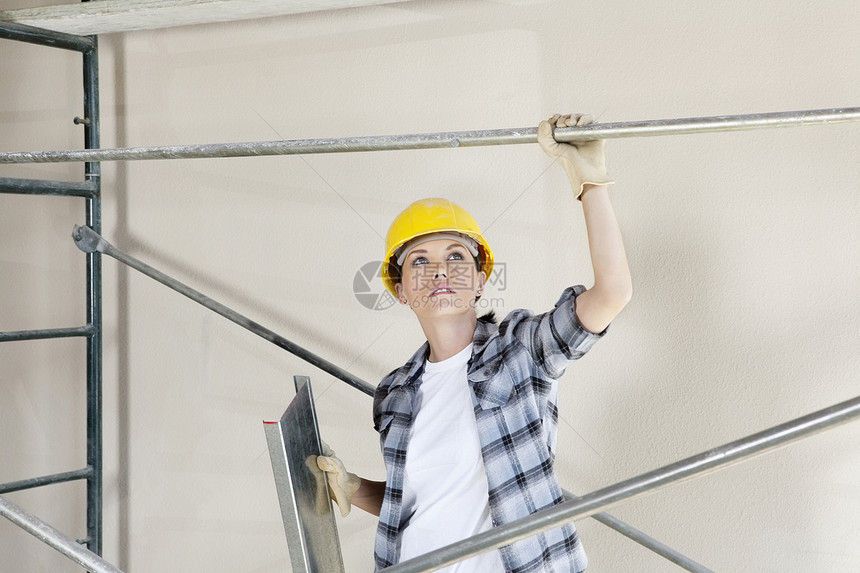 中年女性建筑师站在建筑工地脚手架下抬头看图片