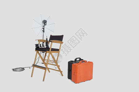 影棚电灯主任的椅子和反射伞 工作室里有手提箱背景