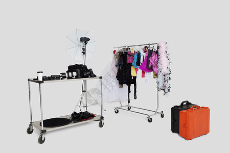 工作室内装有手提箱的衣架和反射伞背景图片