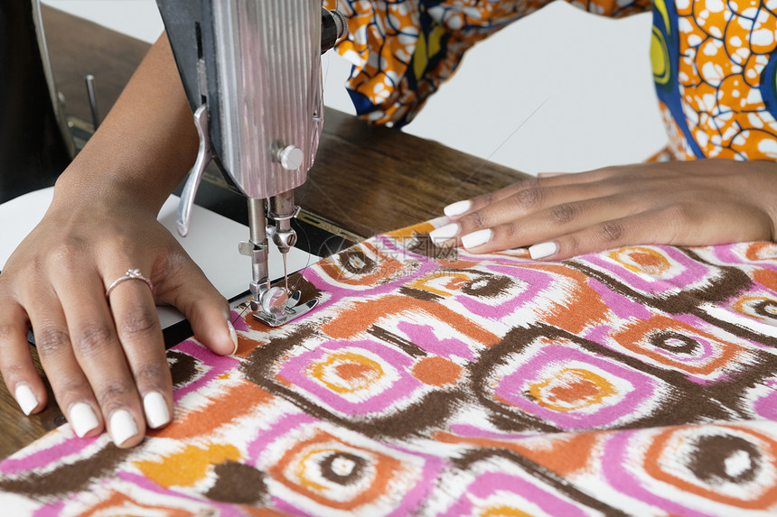 女裁缝在缝纫机上缝制图案布图片