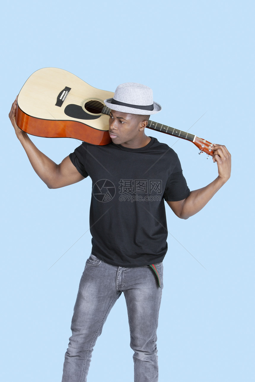 非洲裔美国青年男子携带吉他身穿浅蓝色背景图片