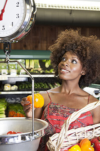 爆炸特价素材非裔美国妇女在超市按比例称量胡椒的非洲女性闲暇沙漠服装休闲成人篮子蔬菜卷发成年杂货店背景
