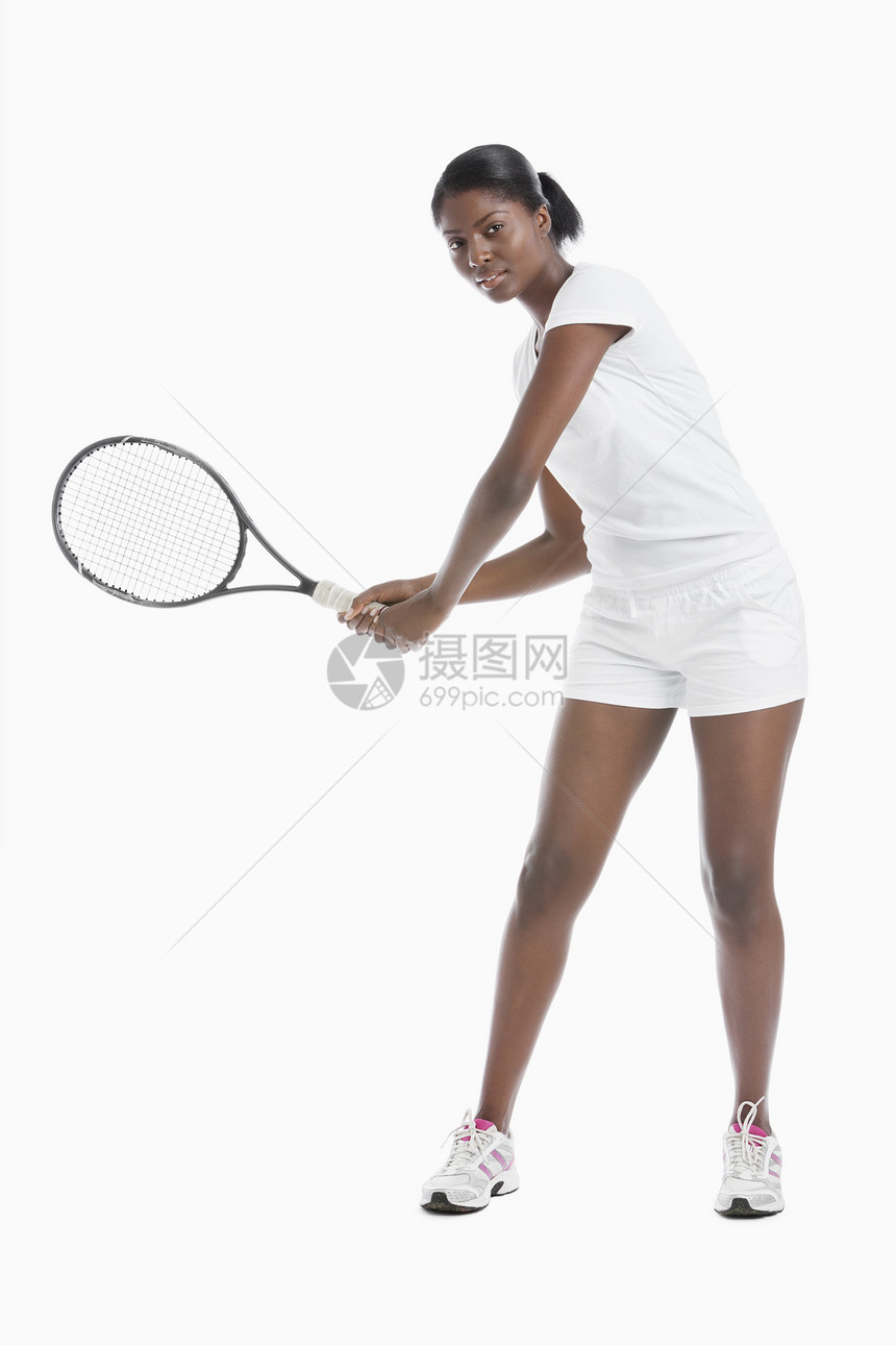 白背景上站着网球拍打的年轻女子肖像图片
