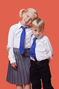 身穿校服 手臂横跨橙色背景的年轻兄弟姊妹肖像搂着高清图片素材