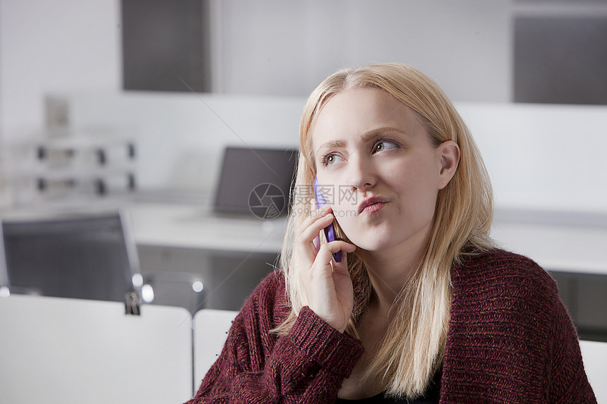 在办公室使用手机的 深思熟虑的年轻女商务人士图片