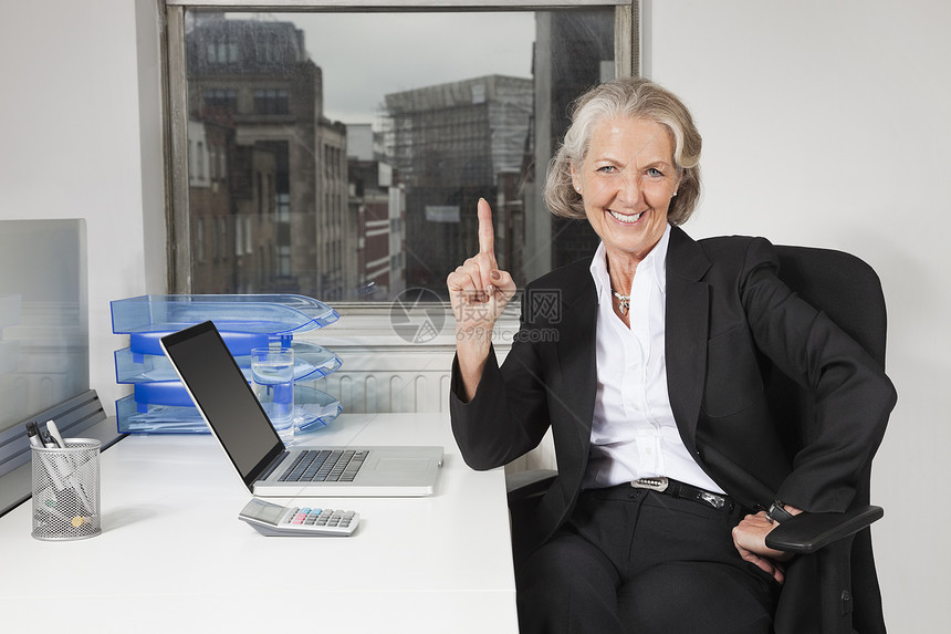 办公室办公桌上膝上型电脑高级女商务人士的肖像图片