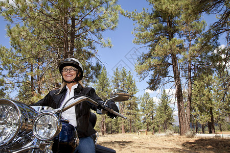 骑摩托车穿越森林的高级女性高龄妇女高清图片