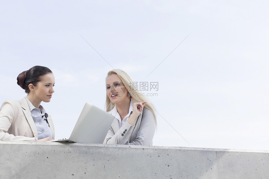 青年女商务人士的低角度视角与笔记本电脑讨论 同时站在天上的阳台上图片