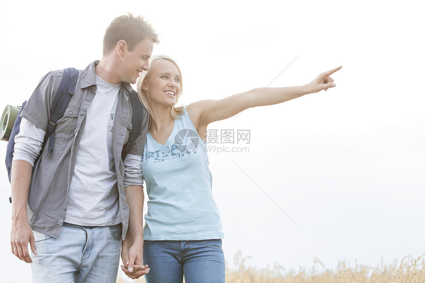 快乐的女徒步旅行者 在露天向野外男人展示一些东西男士农村远足远足者假期情侣手势男朋友场地天空图片
