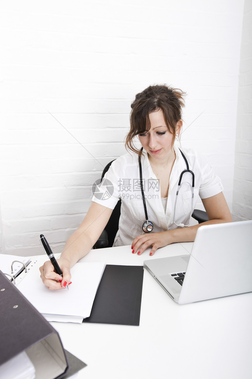 年轻女医生在诊所书桌上写笔记图片