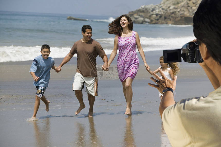 男子录像记录快乐的西班牙裔拉丁家庭在海滩散步图片