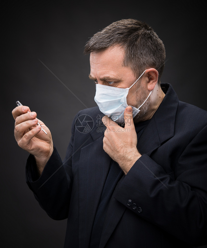 戴带温度计的医务面罩的人疾病流感男人温度感染治疗程序外科预防性情绪图片