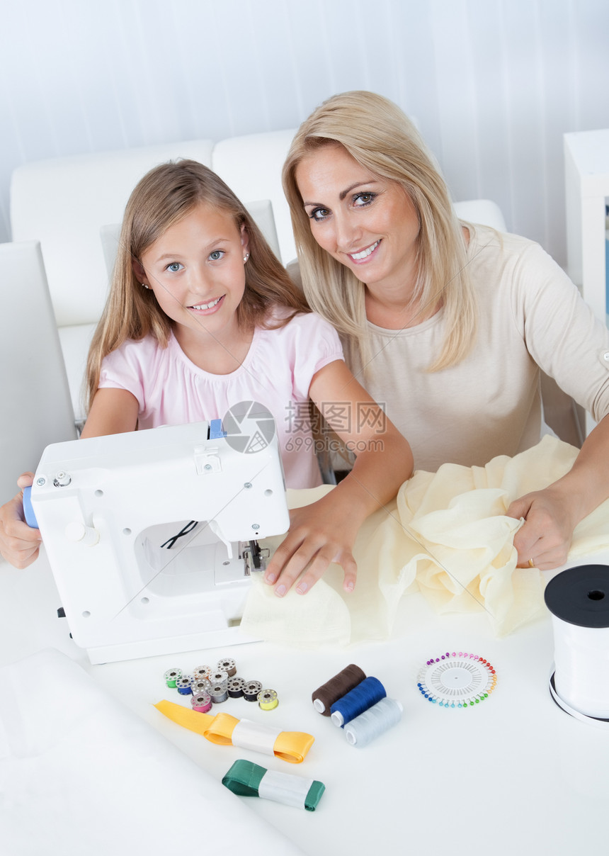 美丽的年轻女孩与母亲一起缝衣房子母性学校女儿线程爱好工作女士老师织物图片