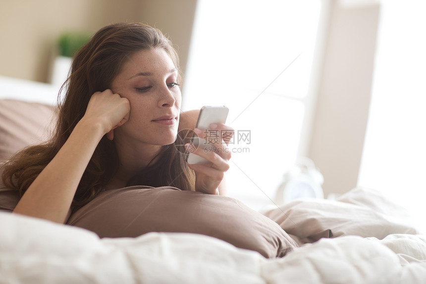 女人在卧室休息寝具技术沟通个性棕色房子家居手机女性短信图片
