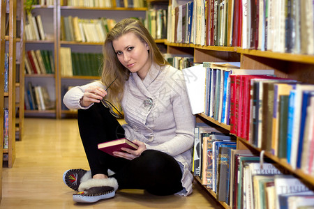 女孩坐在旧图书馆的地板上货架地面女性大学职业教育书架图书青少年衣架背景图片
