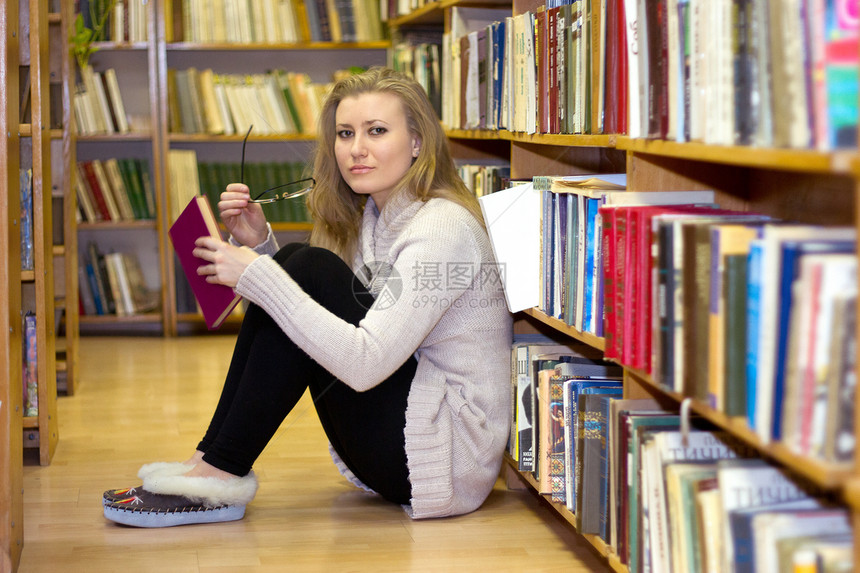女孩坐在旧图书馆的地板上衣架微笑靴子书架大学青少年职业阅读教育毛衣图片