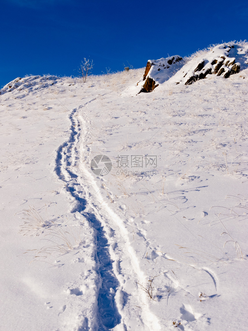 深雪上山丘雪鞋在开阔的山坡上的足迹图片