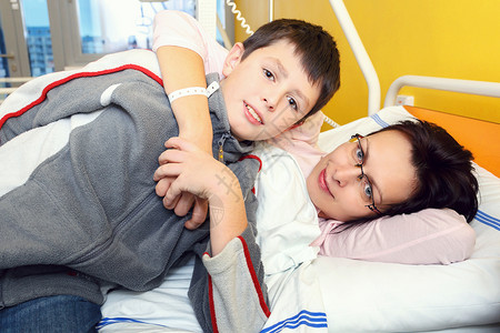 与儿子一起躺在医院的中年悲痛和悲伤的中年妇女肺炎访问收容所女孩卫生思维诊所药品中年人医务室背景图片