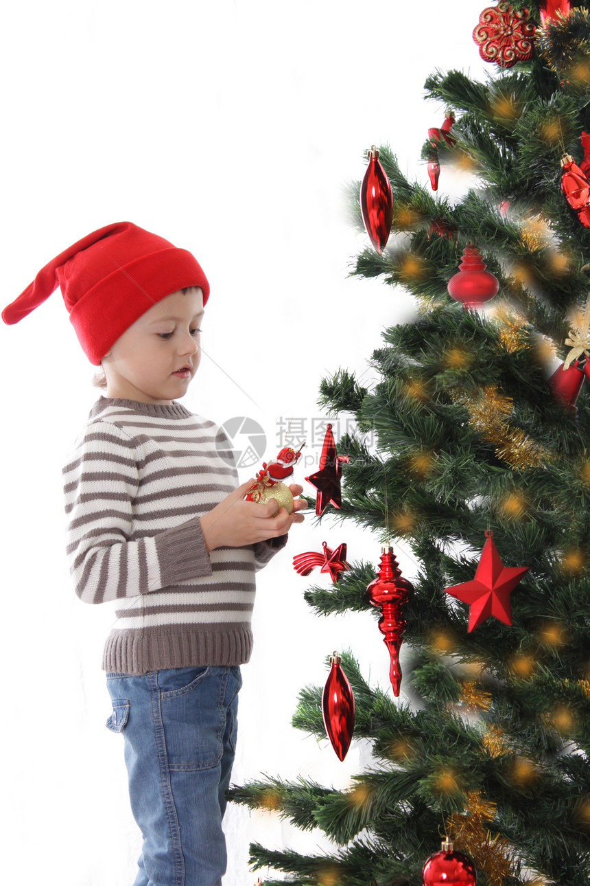 圣诞树上装饰圣诞礼帽的男孩图片