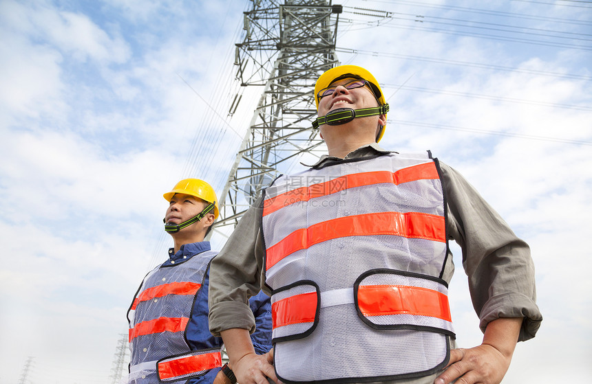 两名工人站在电塔前的电线塔前电气导师工作工程师商业电压安全帽专家发电机力量图片