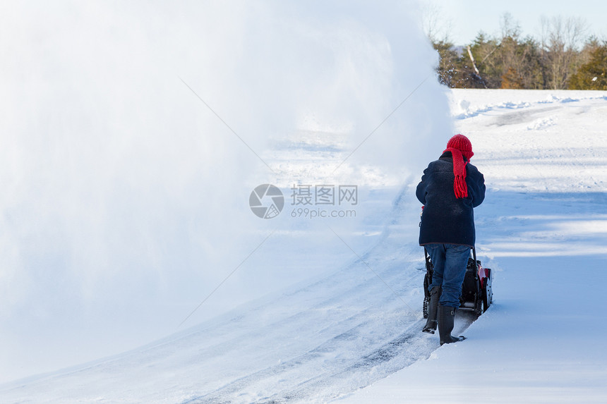 高级妇女与吹雪者清扫车打扫机器住宅驾驶冷冻工作天气退休季节降雪图片