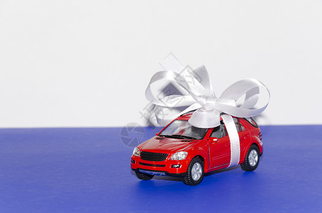 红色车 带白丝带玩具磁带宏观白色蓝色礼物桌子背景图片