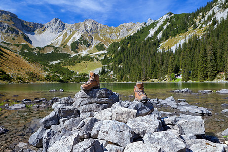鞋山在阿尔卑斯湖的岩石上徒步步行鞋背景