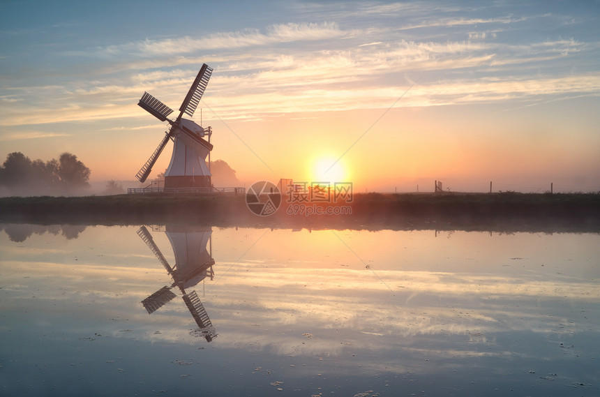 日出时在河流中反射的荷兰风车图片