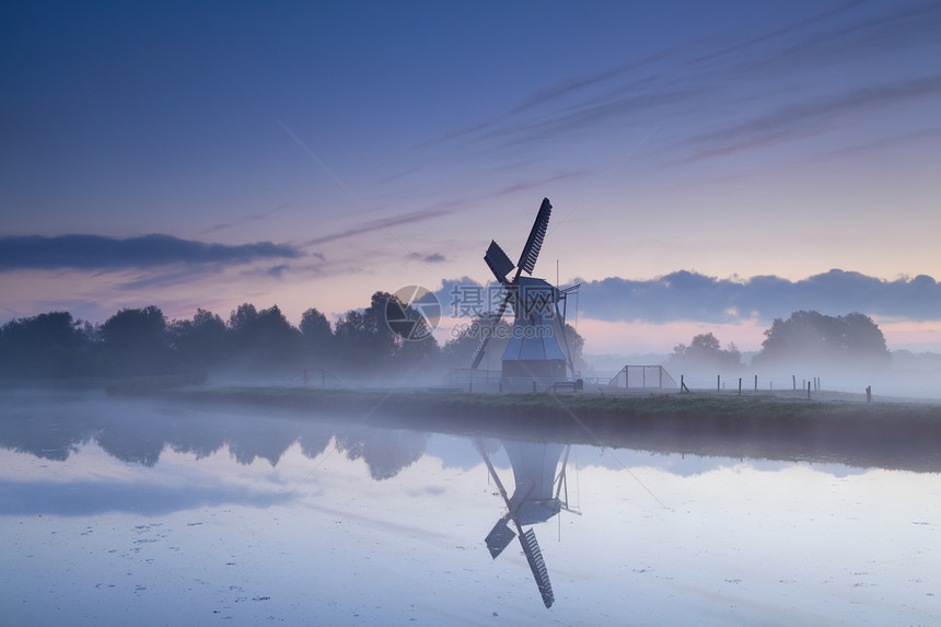 荷兰风车在日出雾的河流中反射图片