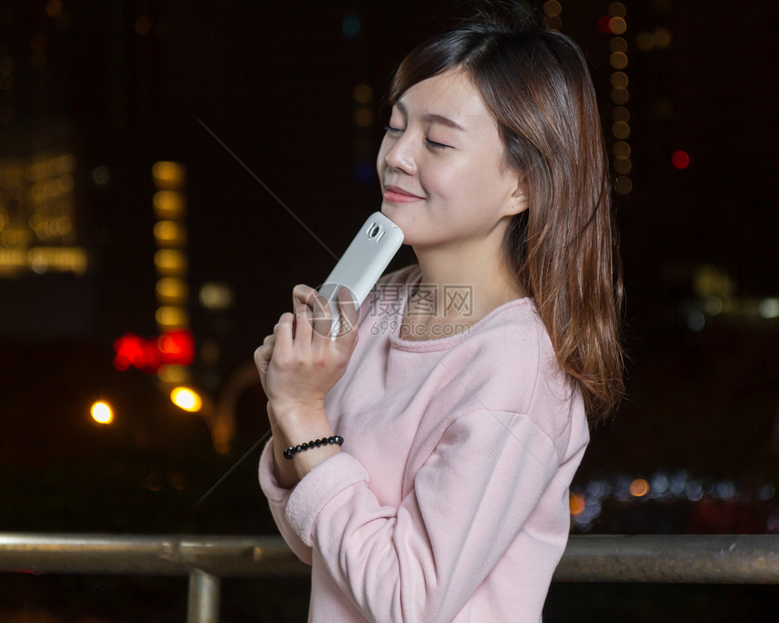 有吸引力的亚洲女性用亮光手机接着手机夜生活精英城市女士女孩魅力图片