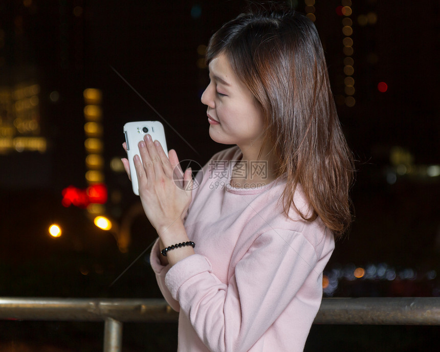 有吸引力的亚洲女性用亮光手机接着手机女孩女士魅力精英夜生活城市图片