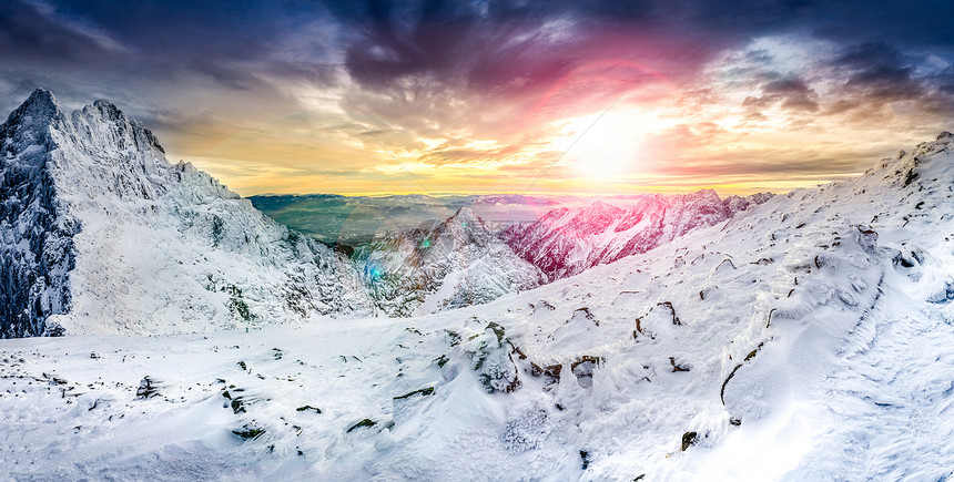 在多彩日落时白色冬季山脉的全景图片