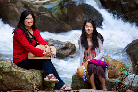 坐在河边的亚洲母亲和女儿坐着高清图片素材