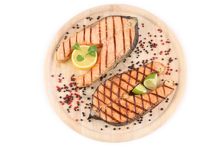 两条鲑鱼牛排在盘子上柠檬油炸橙子红色粉色鱼片木头蔬菜黑色食谱背景