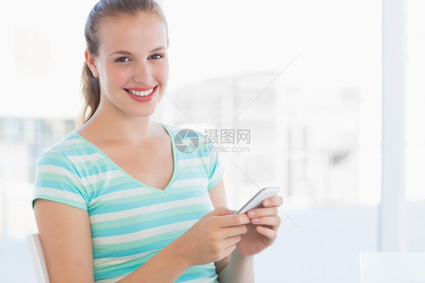 一位美丽的年轻女子的文字按摩肖像微笑办公室手机头发条纹女性沟通电话短信拨号图片
