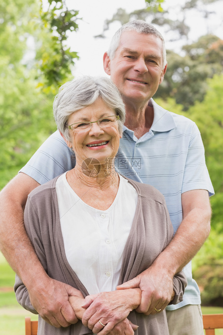 高级男子从后面的公园里抱女人夫妻闲暇享受女性老年成人树木男人亲热感情图片