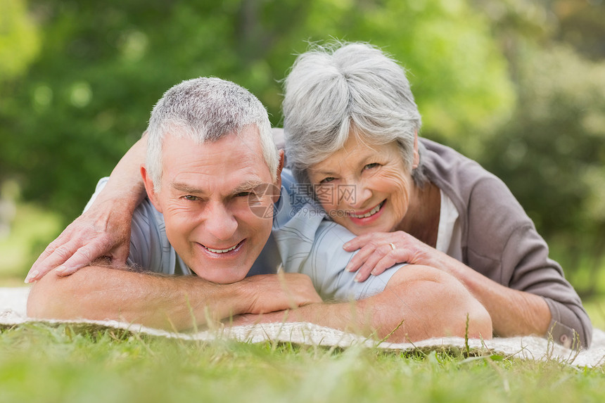 躺在公园里笑着放松的老夫妇女性人员亲热退休说谎老年男人闲暇地毯夫妻图片