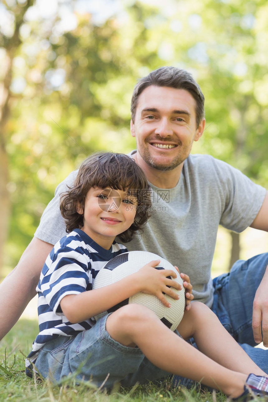 父亲和儿子 橄榄球坐在草地上图片