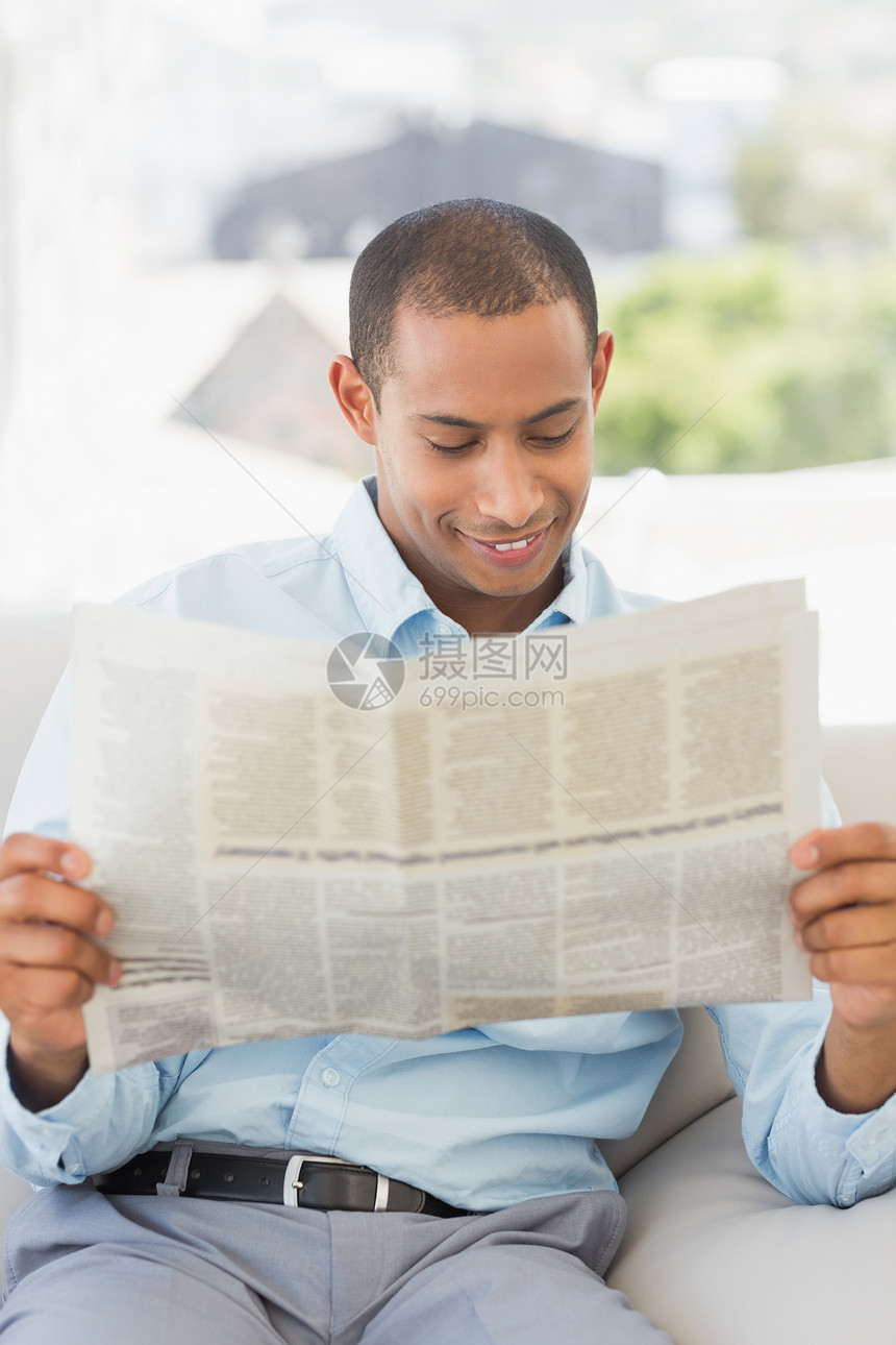 微笑的商务人士在沙发上阅读报纸专注办公室公司长椅衬衫员工商务职场混血男性图片