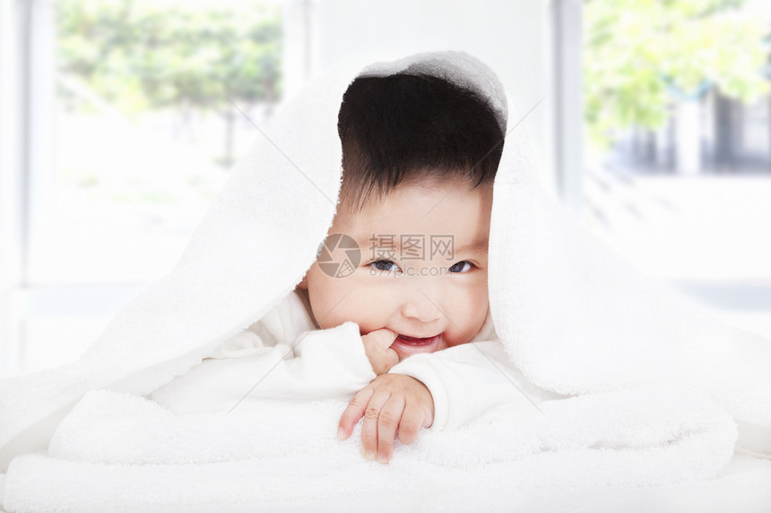 在毛毯或毛巾下吸手指的亚洲婴儿图片