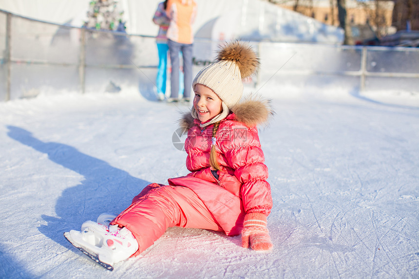 秋天后 可爱的小女孩坐在冰上 穿着溜冰鞋坐着冰雪锻炼喜悦婴儿溜冰者童年帮助女孩闲暇溜冰场女儿图片