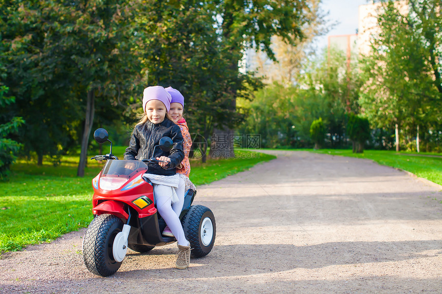 可爱的小女孩 在绿色公园骑着孩子的摩托车自行车夹克童年裙子女孩玩具快乐运动公园运输图片